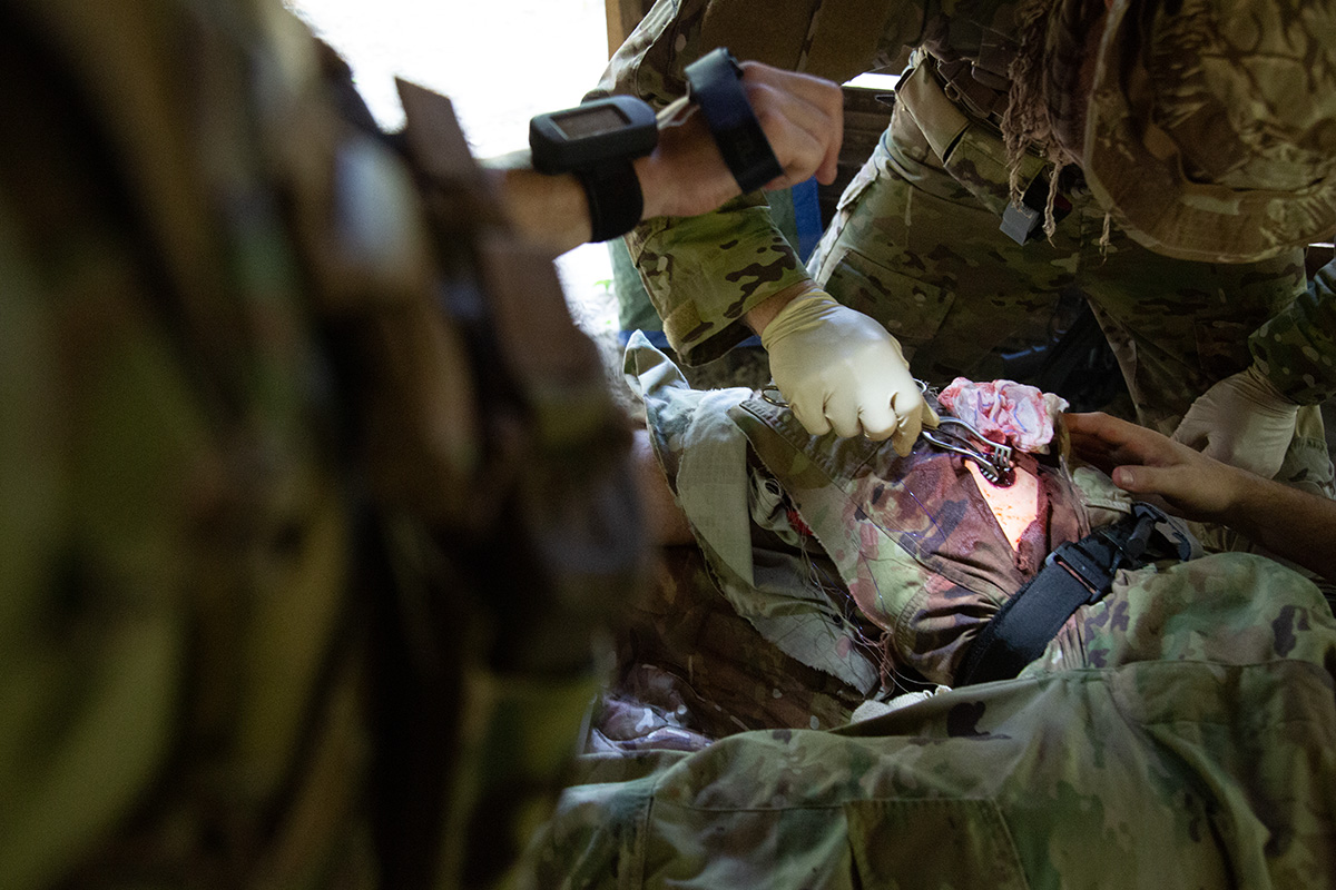 Military personnel applying tourniquet, and treating wound